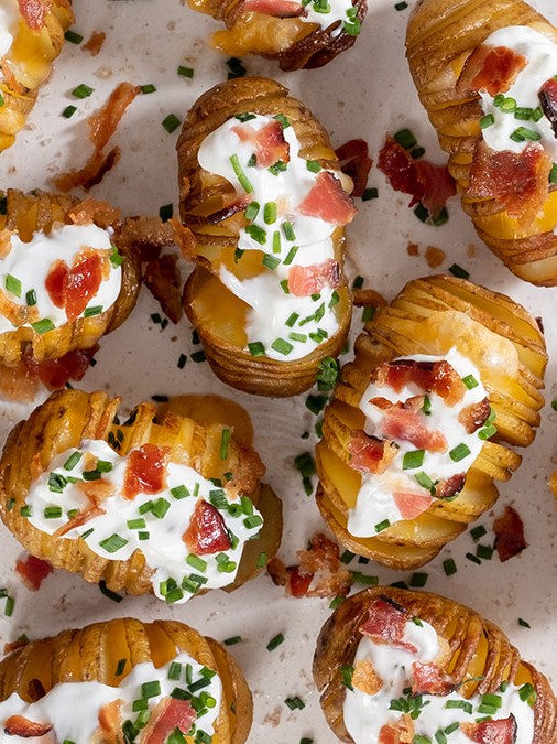 Flatlay image of crispy potatoes with bacon on white plate
